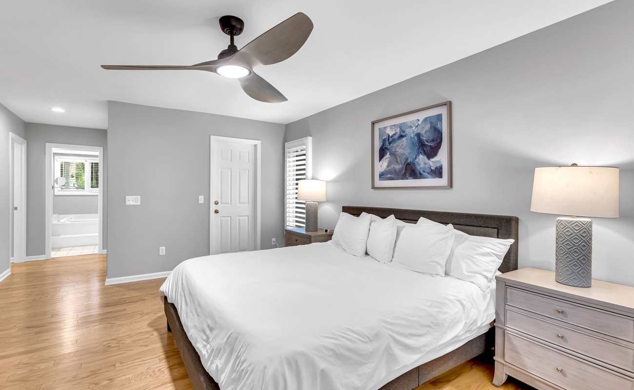 Drift off to sleep in your serene bedroom featuring crisp linens, warm hardwood floors, and gentle ceiling fan breeze.