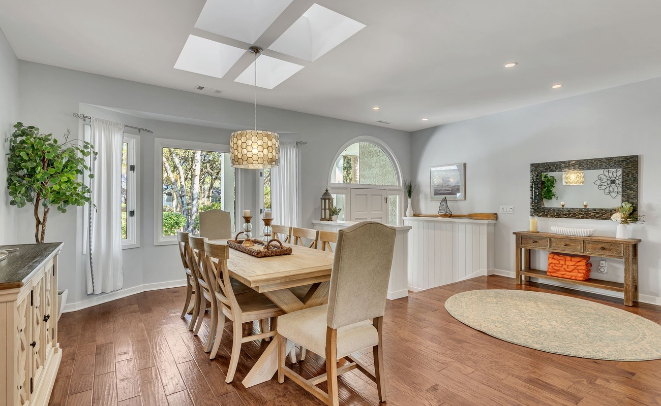 Gather around this inviting dining table where natural light pours through the skylight, creating the perfect setting for memorable meals together.