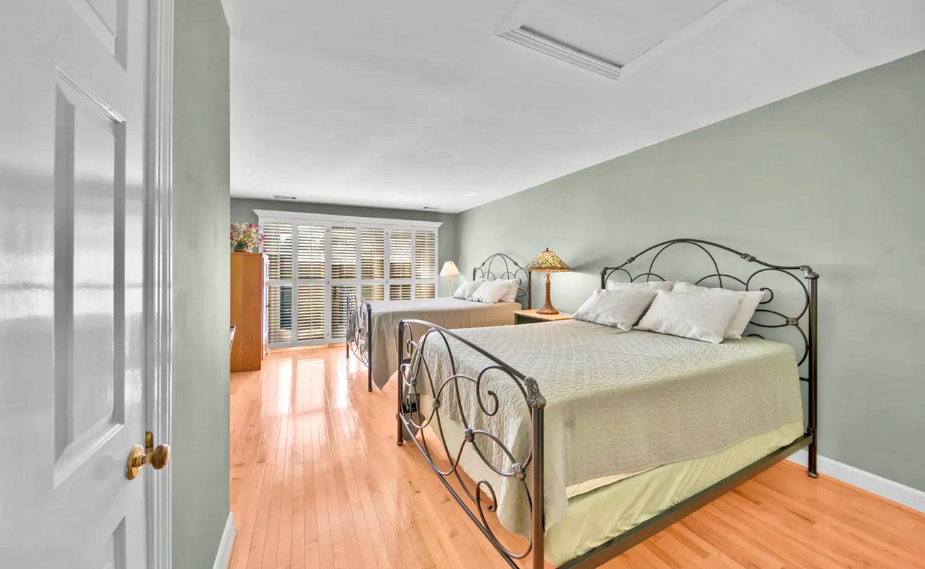 Relax in this soothing bedroom where soft sage walls and warm hardwood floors create your peaceful retreat sanctuary.