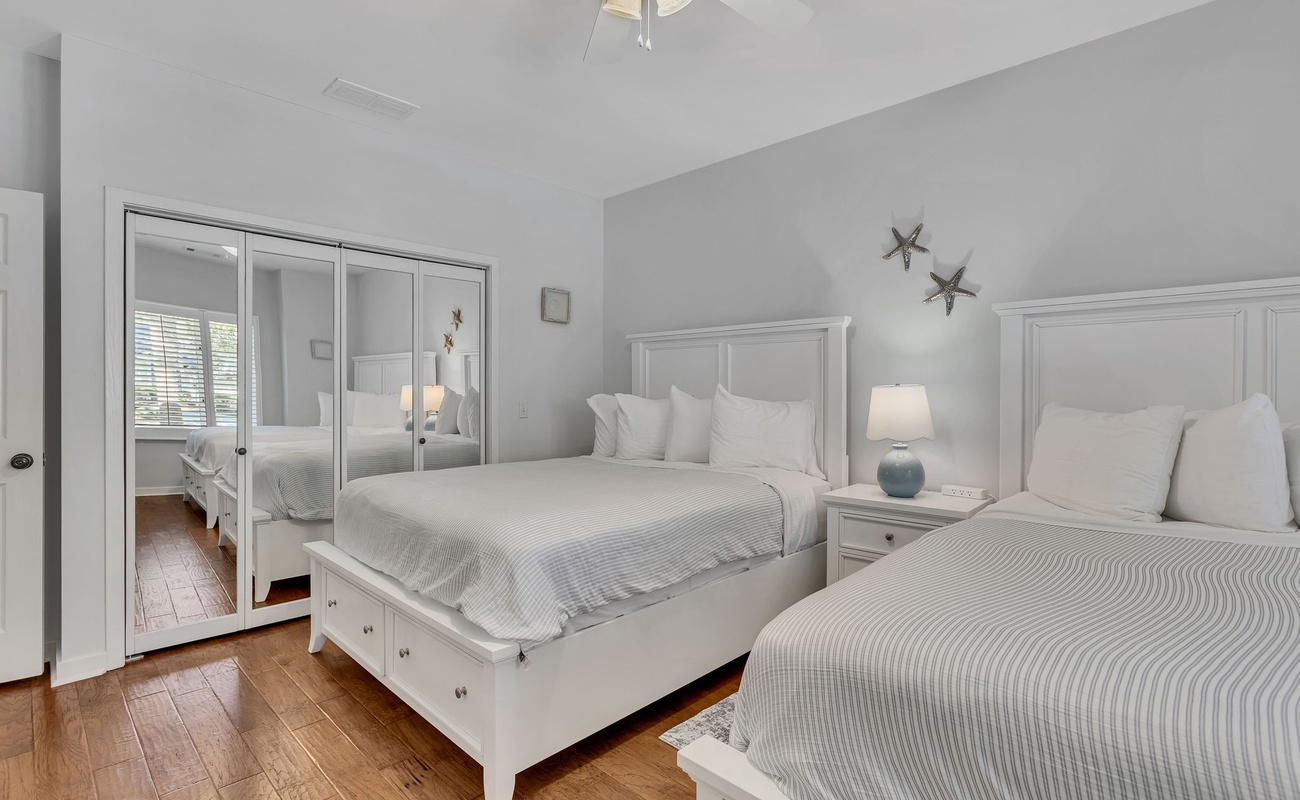 Drift off to peaceful sleep in this serene bedroom featuring two comfortable beds with crisp linens and warm lighting.