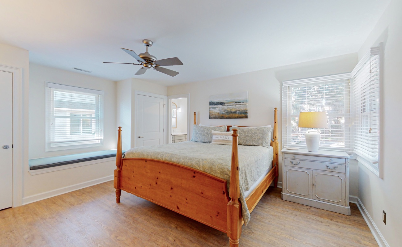 Rest peacefully in your charming bedroom with warm wood furnishings, soft linens, and natural light from multiple windows.