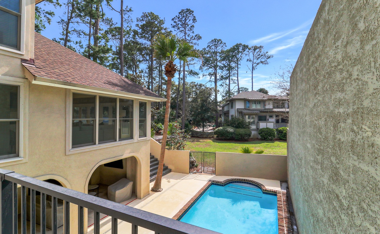 Private pool area with mature oak trees and spacious lawn, creating a peaceful residential setting for the vacation rental property.