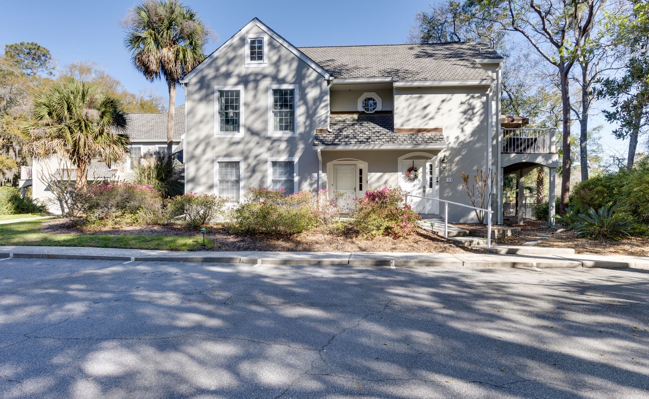 Charming coastal home with mature landscaping and palm trees in a peaceful neighborhood setting.