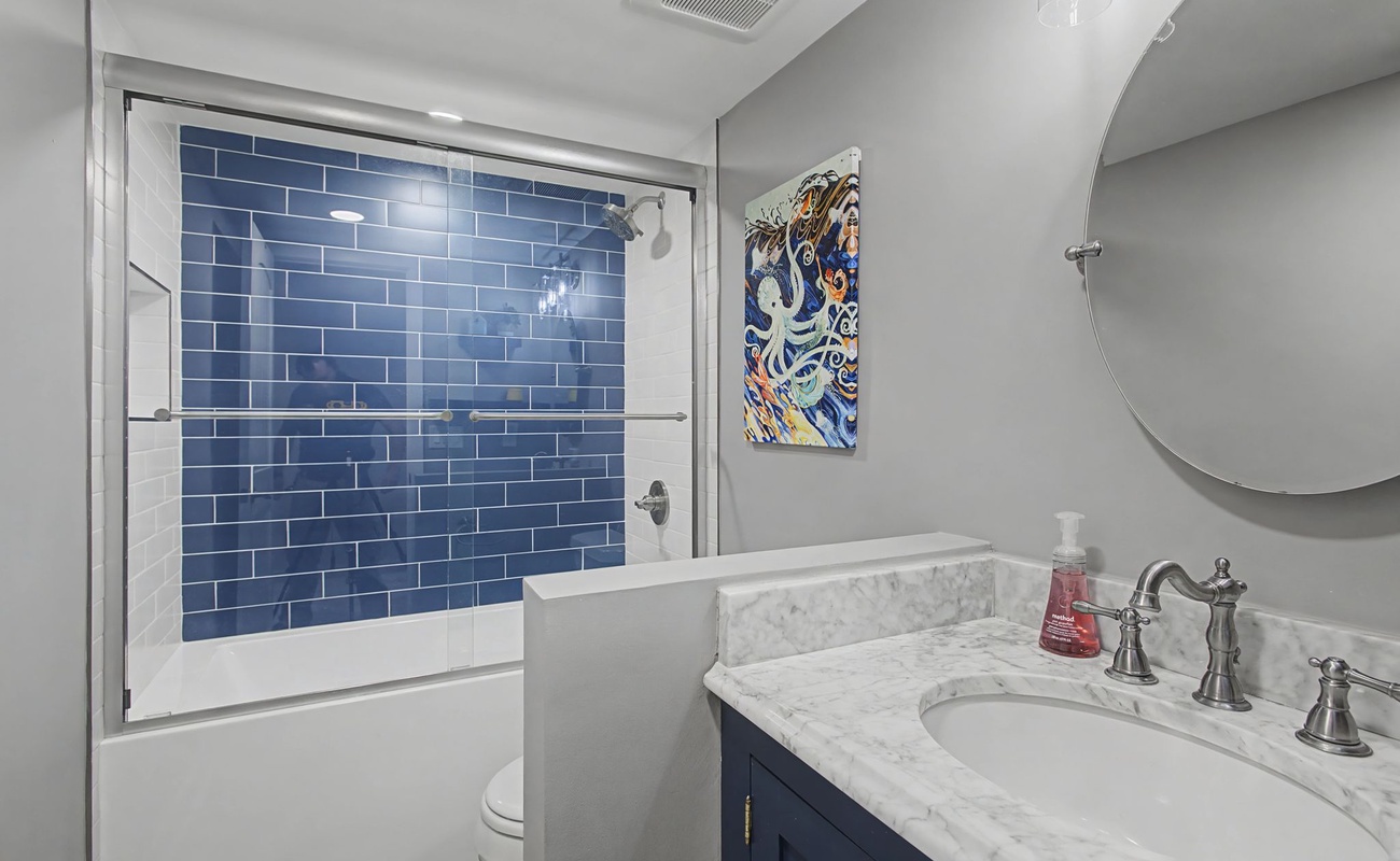 Your elegant bathroom features a marble vanity and striking blue subway tile shower, creating a spa-like retreat for your morning routine.