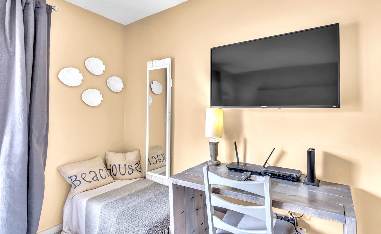 Settle into your cozy retreat with beach-themed décor, flat-screen TV, and charming work nook bathed in warm natural light.