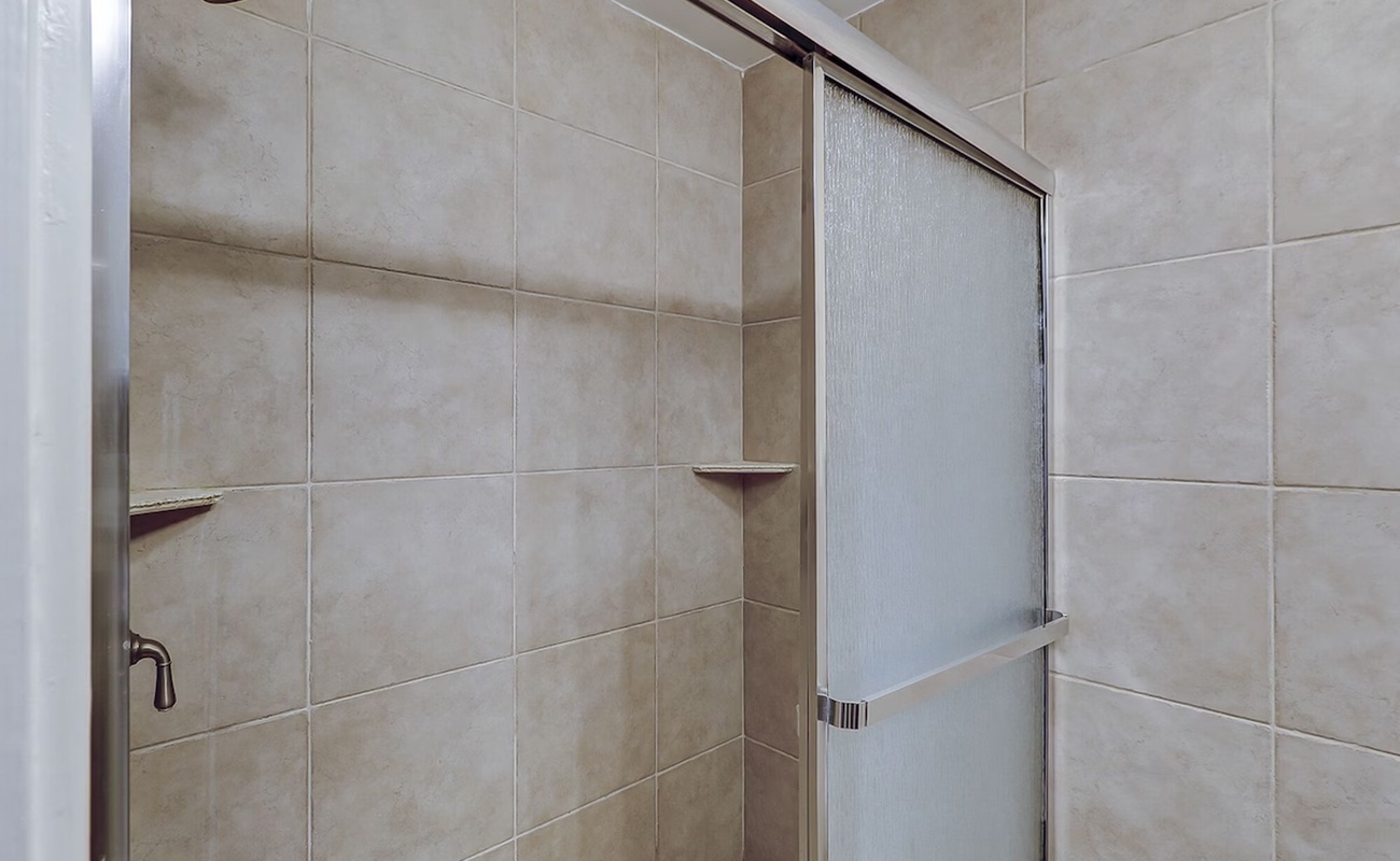 Step into your private spa-like shower with elegant tiled walls and modern glass doors for a refreshing start to your day.