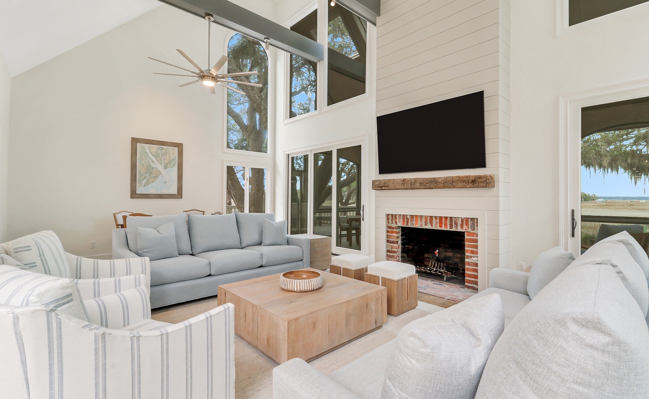 Relax in this stunning living room with soaring ceilings, where natural light pours through expansive windows while you enjoy the cozy fireplace.