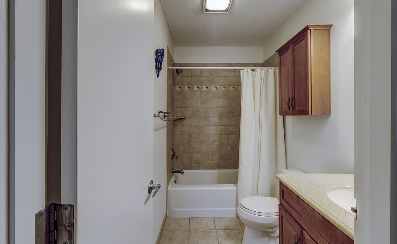 Your private bathroom features a relaxing tub-shower combo with elegant tile work and warm wood cabinetry for all your essentials.
