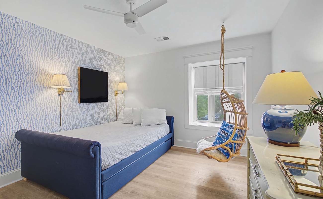 Rest peacefully in your stylish bedroom featuring elegant blue accents and a charming hanging chair for quiet moments.