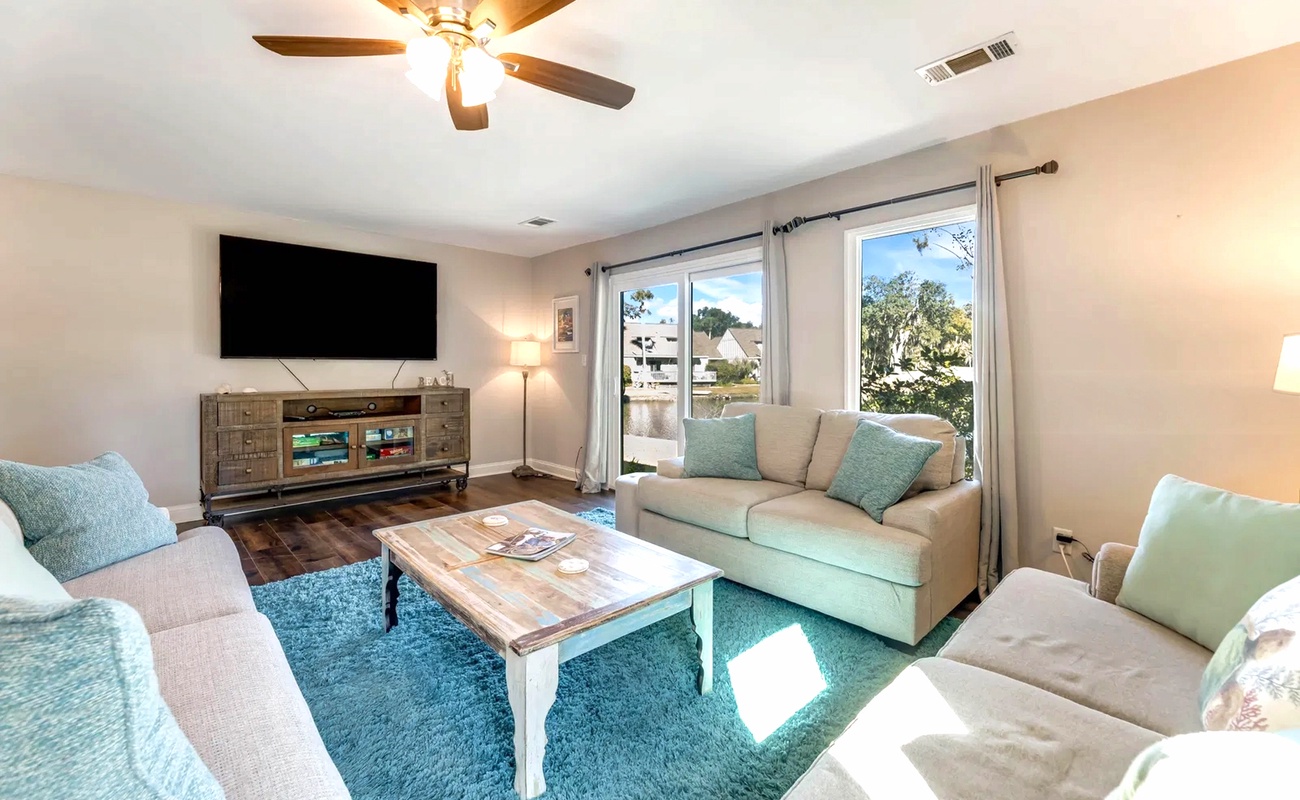 Unwind in your bright living space with comfortable seating, entertainment center, and peaceful neighborhood views through large windows.