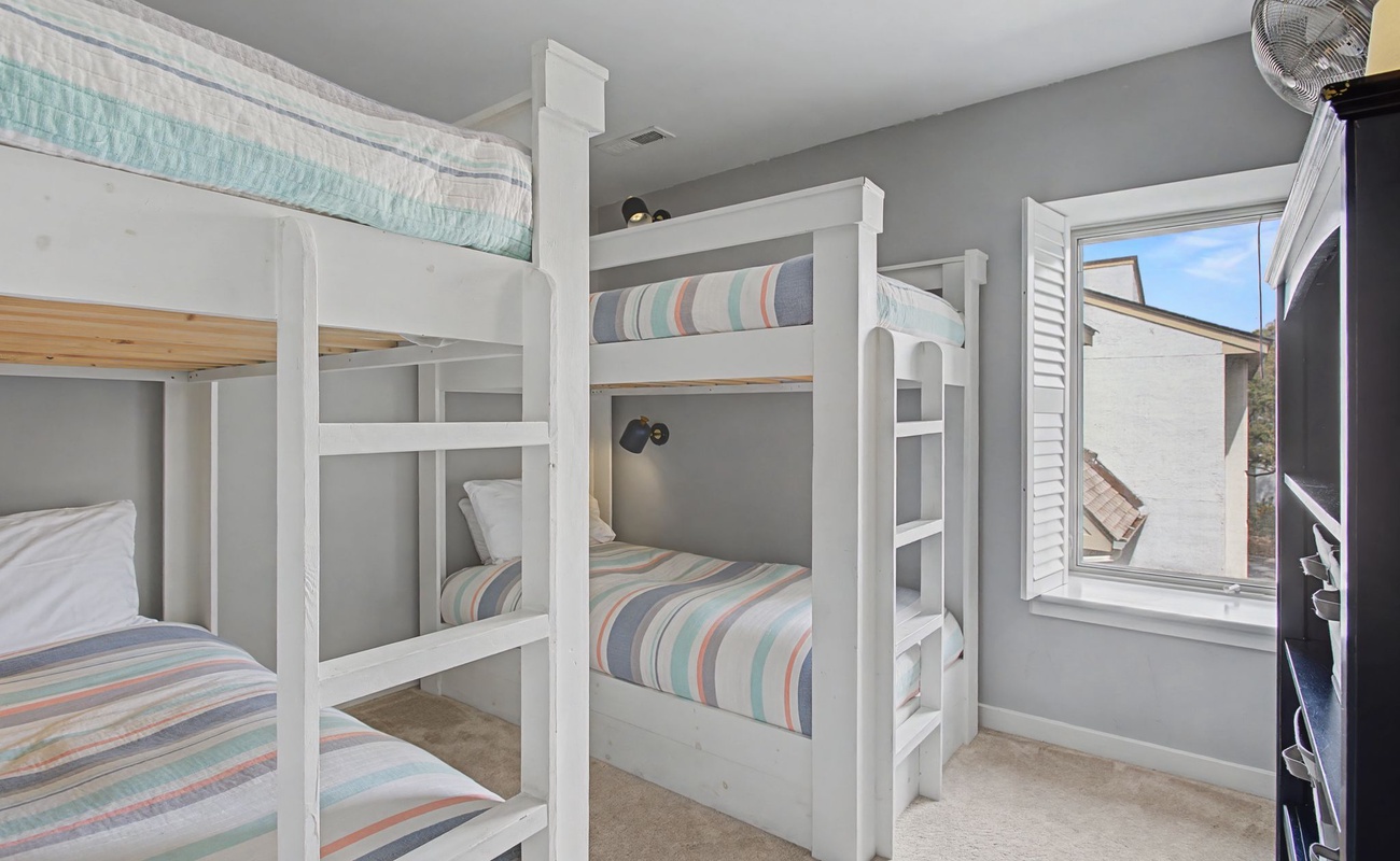Your group will love these custom bunk beds with individual reading lights and cozy striped linens for perfect shared adventures.