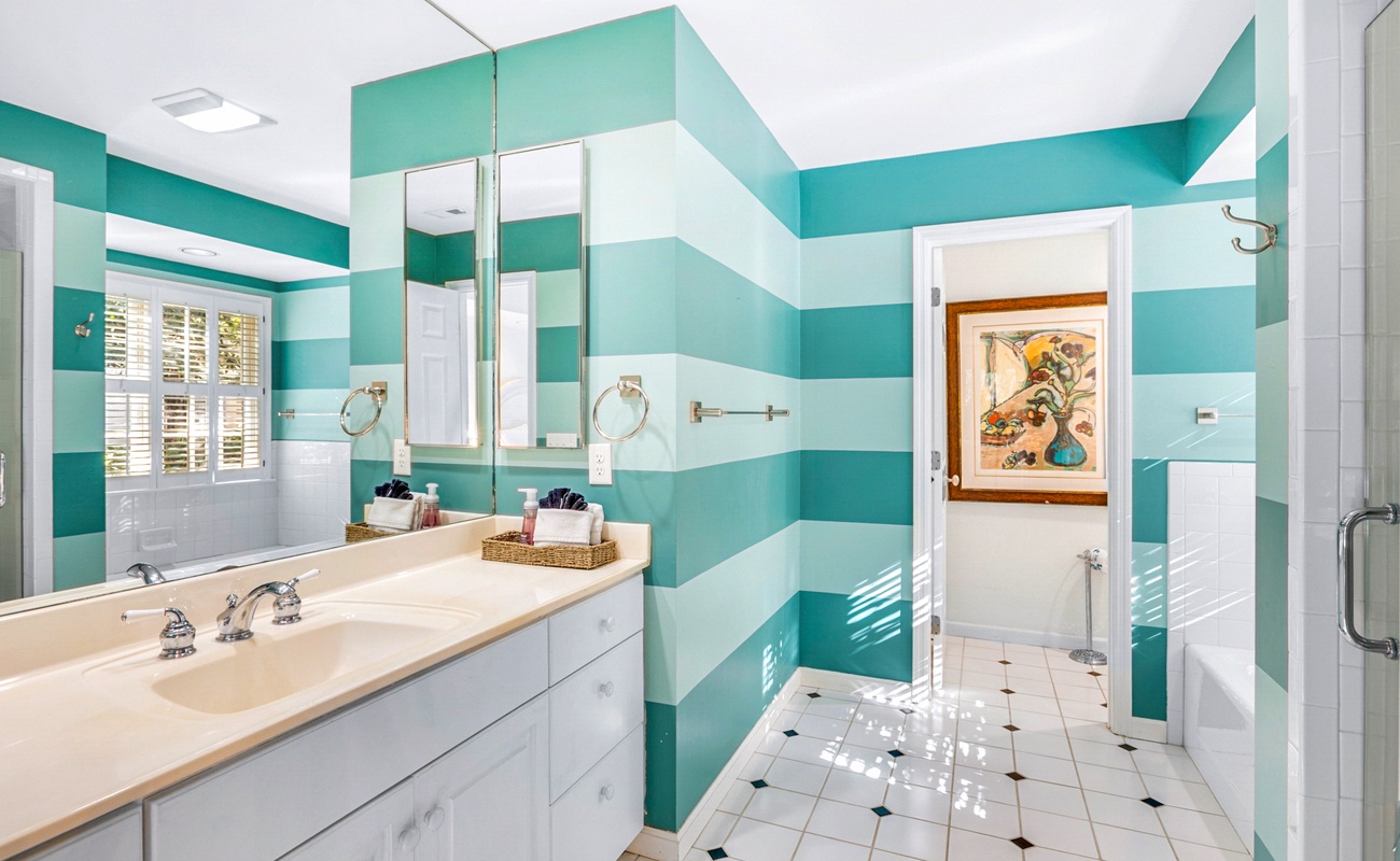 Step into your bright coastal bathroom featuring bold turquoise stripes, spacious vanity, and cheerful natural light streaming through plantation shutters.