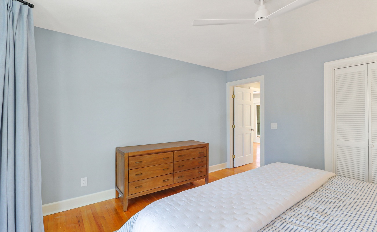 Drift off in your peaceful bedroom with soft blue walls, warm hardwood floors, and a gentle ceiling fan overhead.