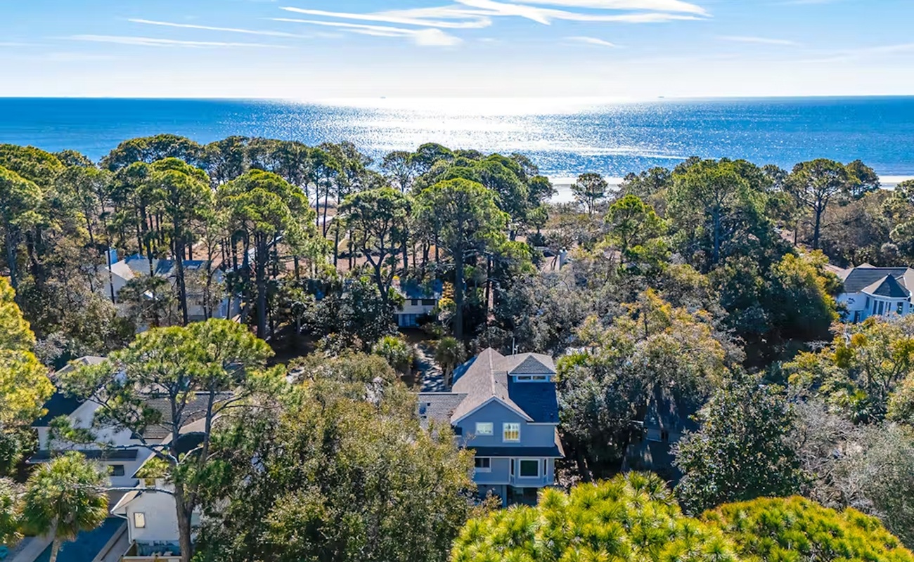 Coastal retreat nestled among mature trees with pristine beach just beyond the tree line.