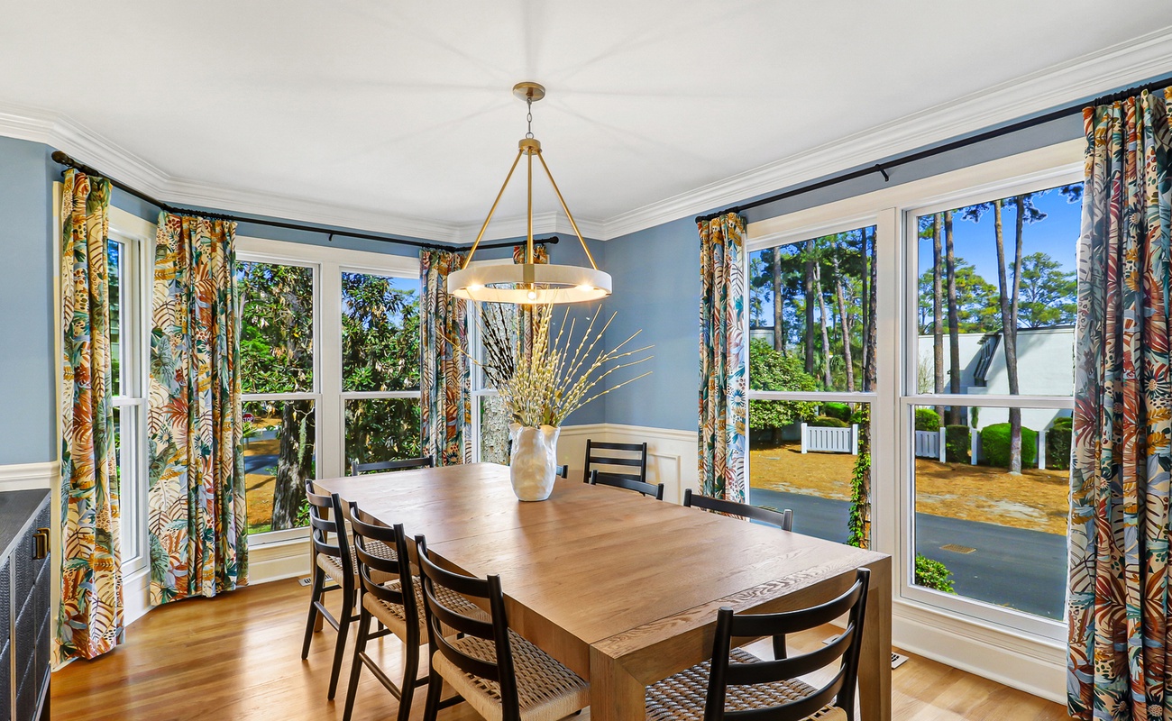 Gather around your elegant dining table where tropical curtains frame garden views and warm light creates perfect moments for memorable meals together.