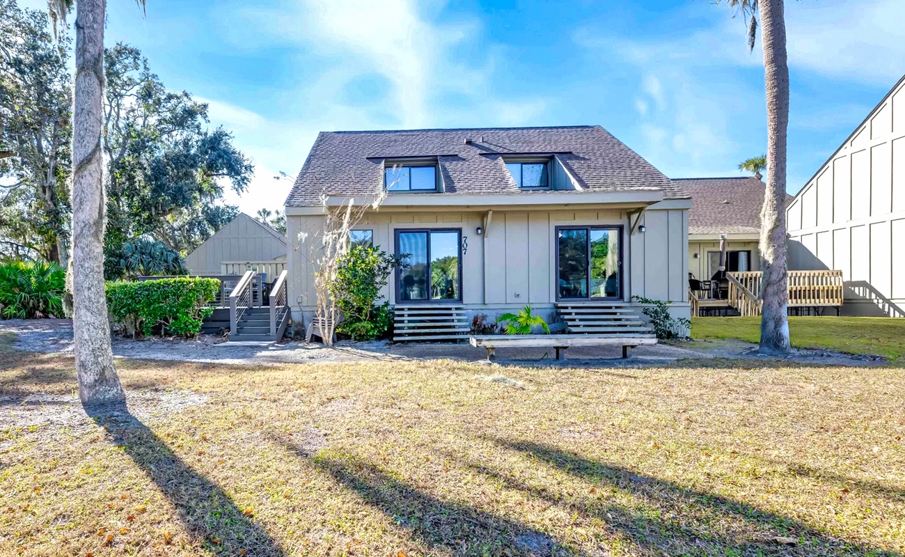 Modern coastal retreat featuring clean lines, spacious lawn, and mature palms creating a serene setting.