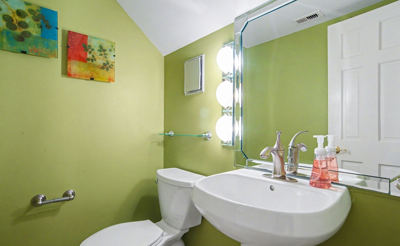Freshen up in your vibrant bathroom featuring modern fixtures and cheerful green walls that create an energizing start to your day.