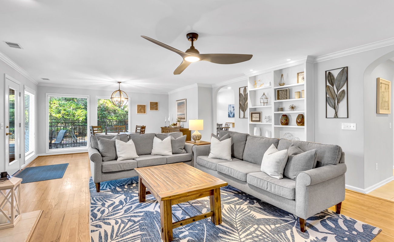 Unwind in your spacious living room with plush gray sofas, stylish built-ins, and peaceful pool views
