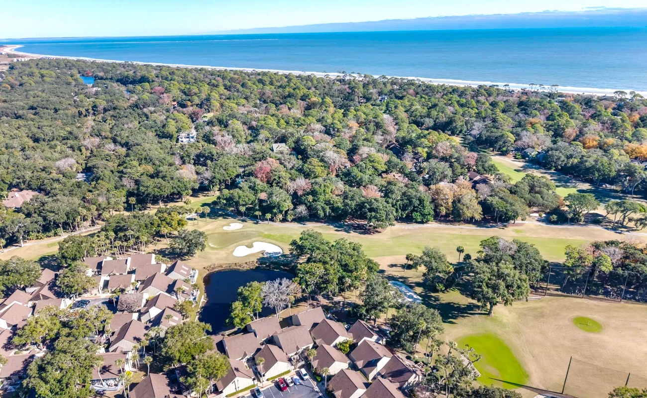 Aerial view showcasing a coastal resort community nestled between pristine beaches and championship golf fairways, surrounded by lush natural landscape.