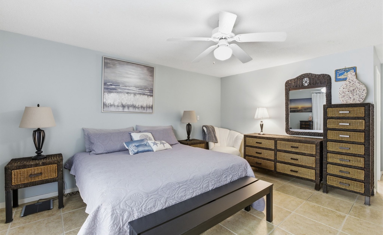 Your peaceful bedroom sanctuary features a comfortable bed, stylish wicker furniture, and coastal artwork to help you unwind completely.