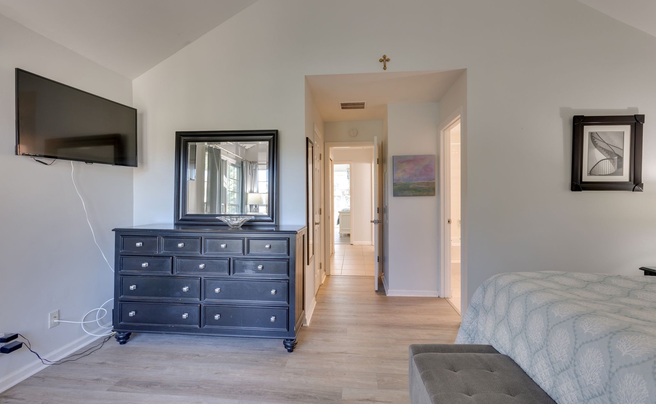 Your elegant bedroom features a spacious layout with stylish dark wood dresser, wall-mounted TV, and convenient storage for all your belongings.
