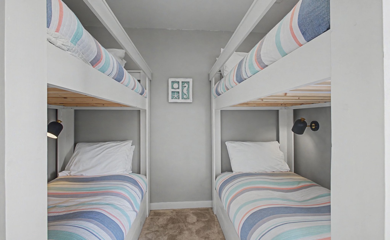 Cozy bunk room with soft striped linens and individual reading lights for your perfect night's rest.