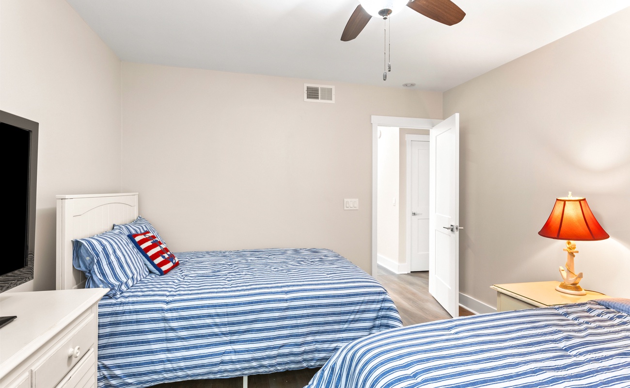 Your cheerful bedroom features double beds with nautical striped linens and warm lighting for restful nights.