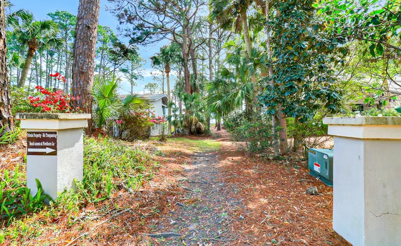 Property entrance with tropical landscaping and mature trees creates a welcoming arrival experience in this lush neighborhood setting.
