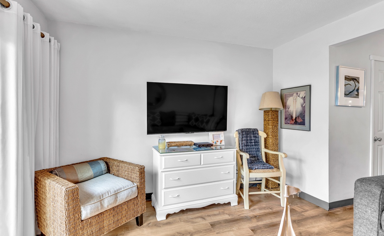 Unwind in your bright living space with wicker seating, wall-mounted TV, and coastal-inspired décor creating the perfect retreat.