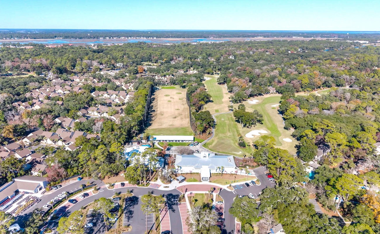 Aerial view showcases the resort's prime location near golf courses and wooded residential areas, with ample parking and easy access.