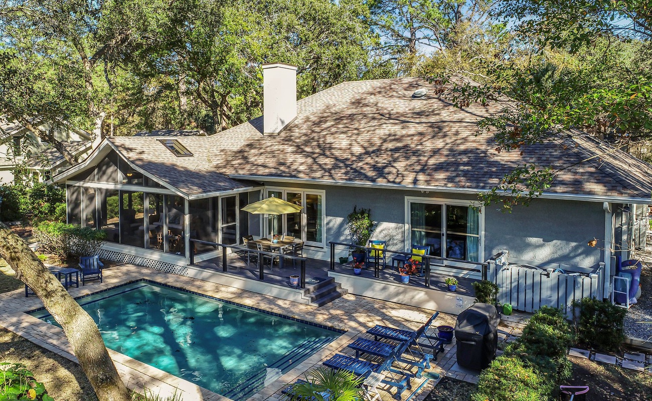Elevated view of vacation rental property featuring pool and outdoor living areas nestled among mature trees.