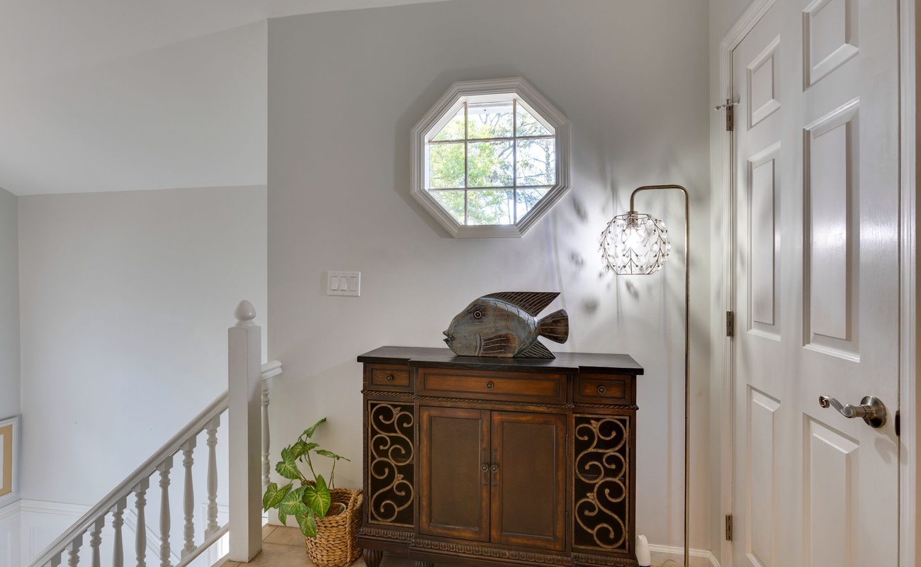 Sunlight streams through your octagonal window, illuminating this charming upstairs hallway with warm natural light and thoughtful coastal touches.