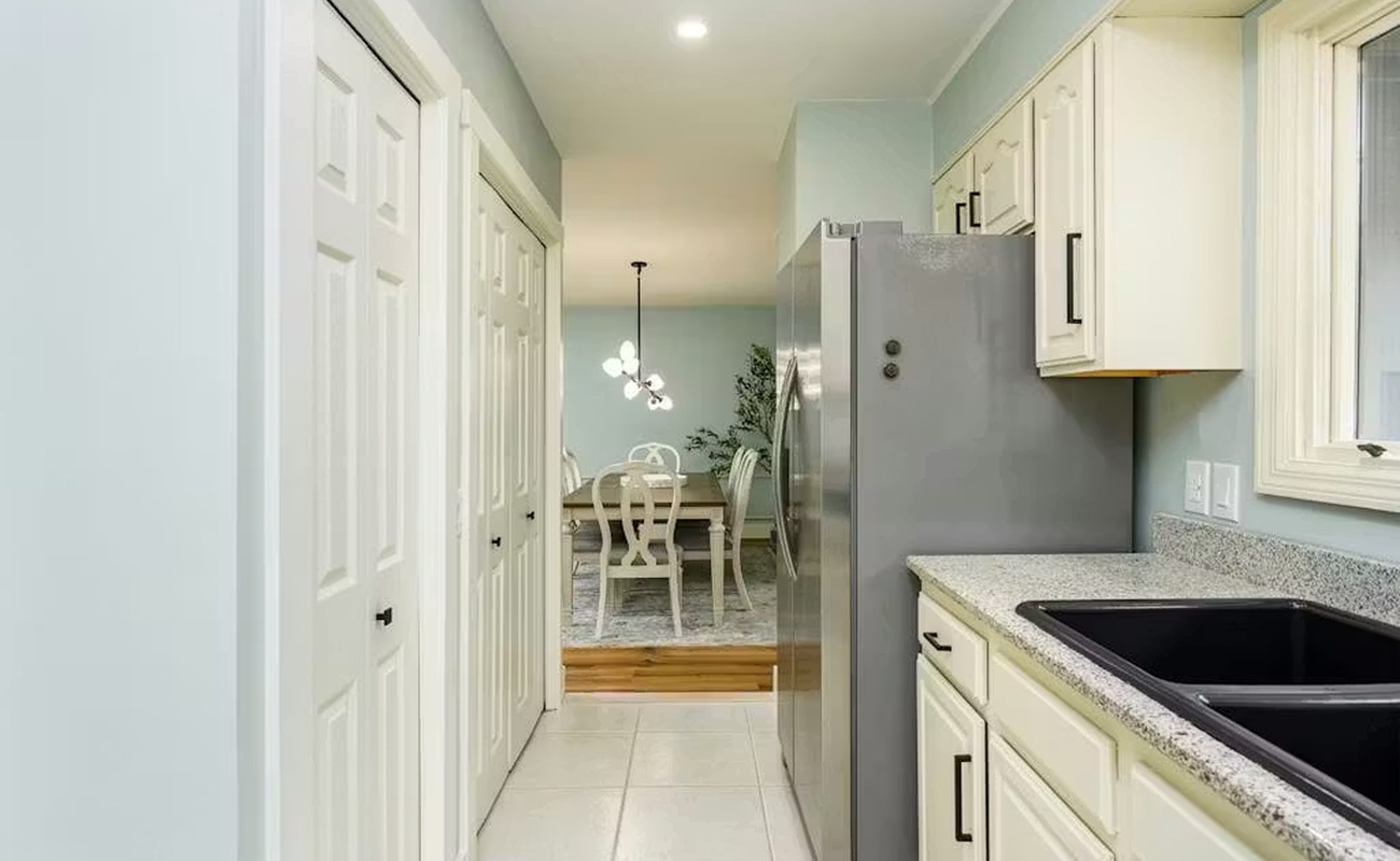 Your sleek galley kitchen features granite counters, white cabinets, and a gleaming stainless steel refrigerator, perfectly equipped for your culinary adventures.