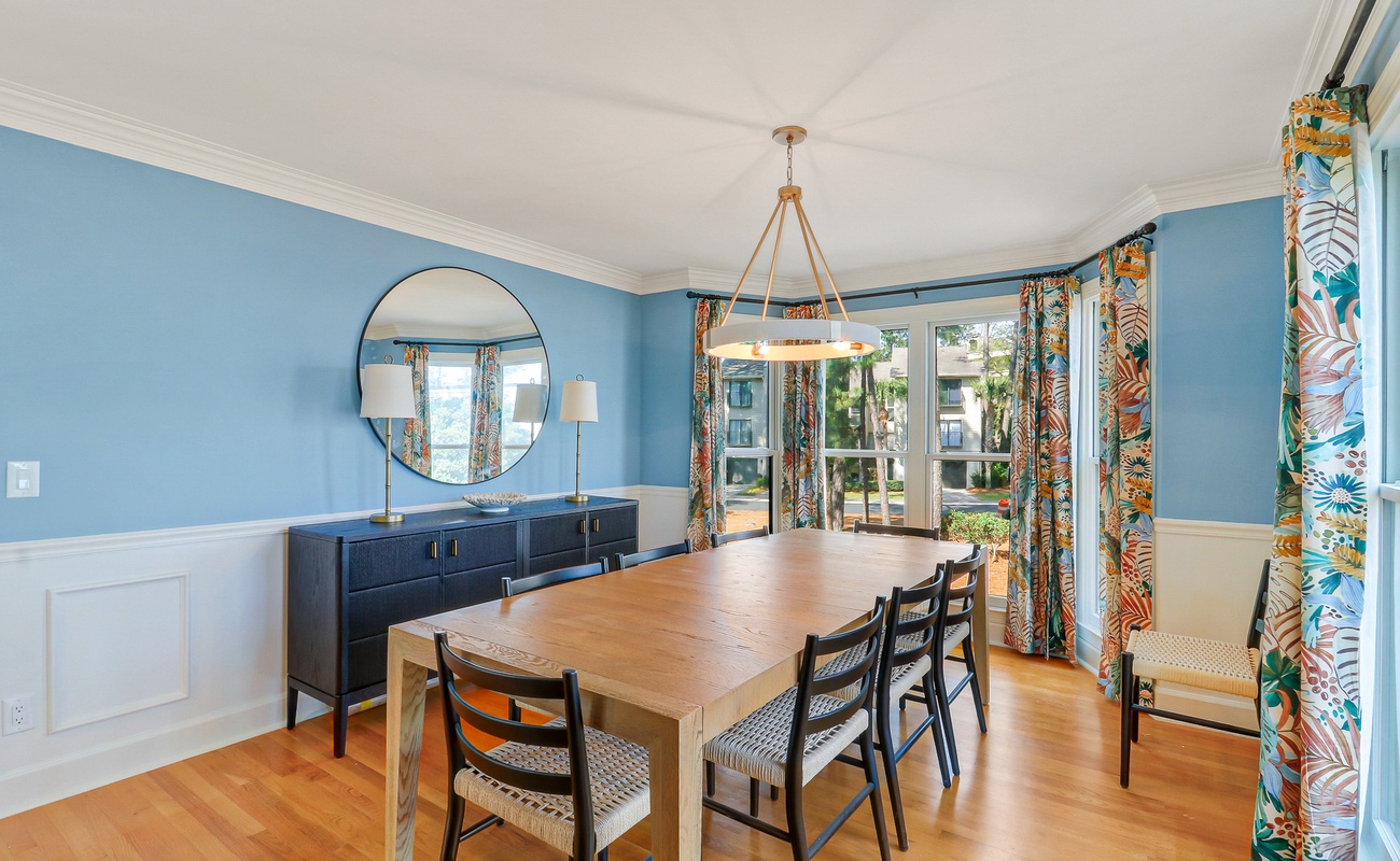 Gather around this elegant dining table where memorable meals await, surrounded by vibrant tropical décor and soft blue walls.