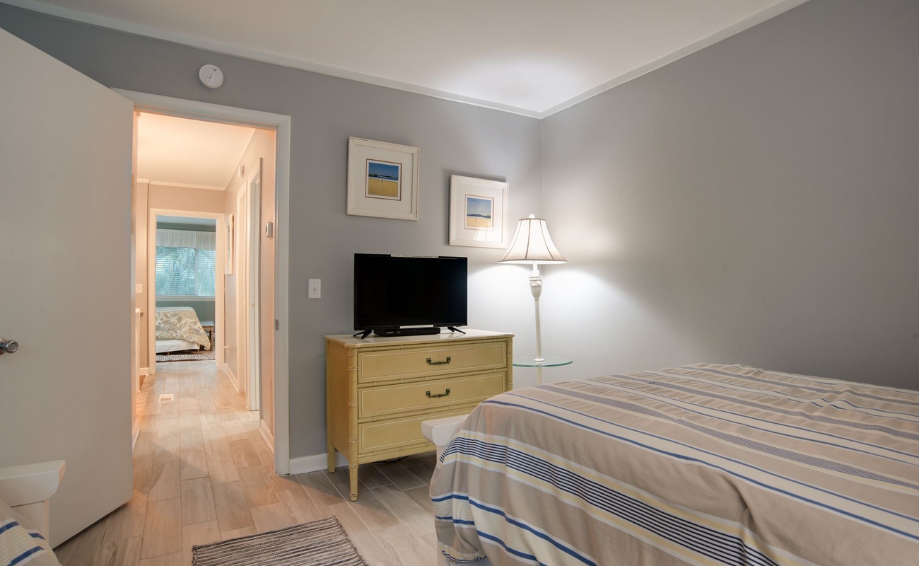 Your peaceful bedroom features soothing gray walls, warm wood floors, and a cozy lamp creating the perfect atmosphere for restful nights.