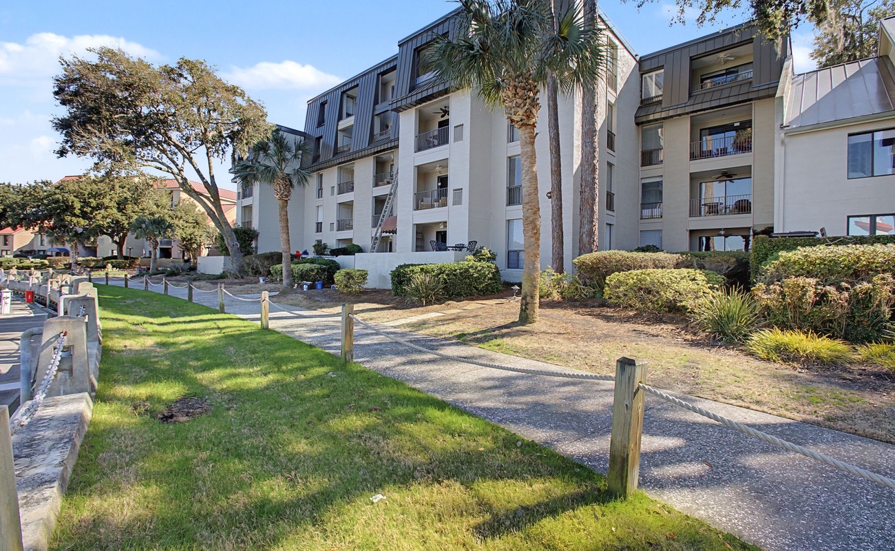 A modern apartment complex set among palm trees and manicured gardens, offering a peaceful residential retreat.