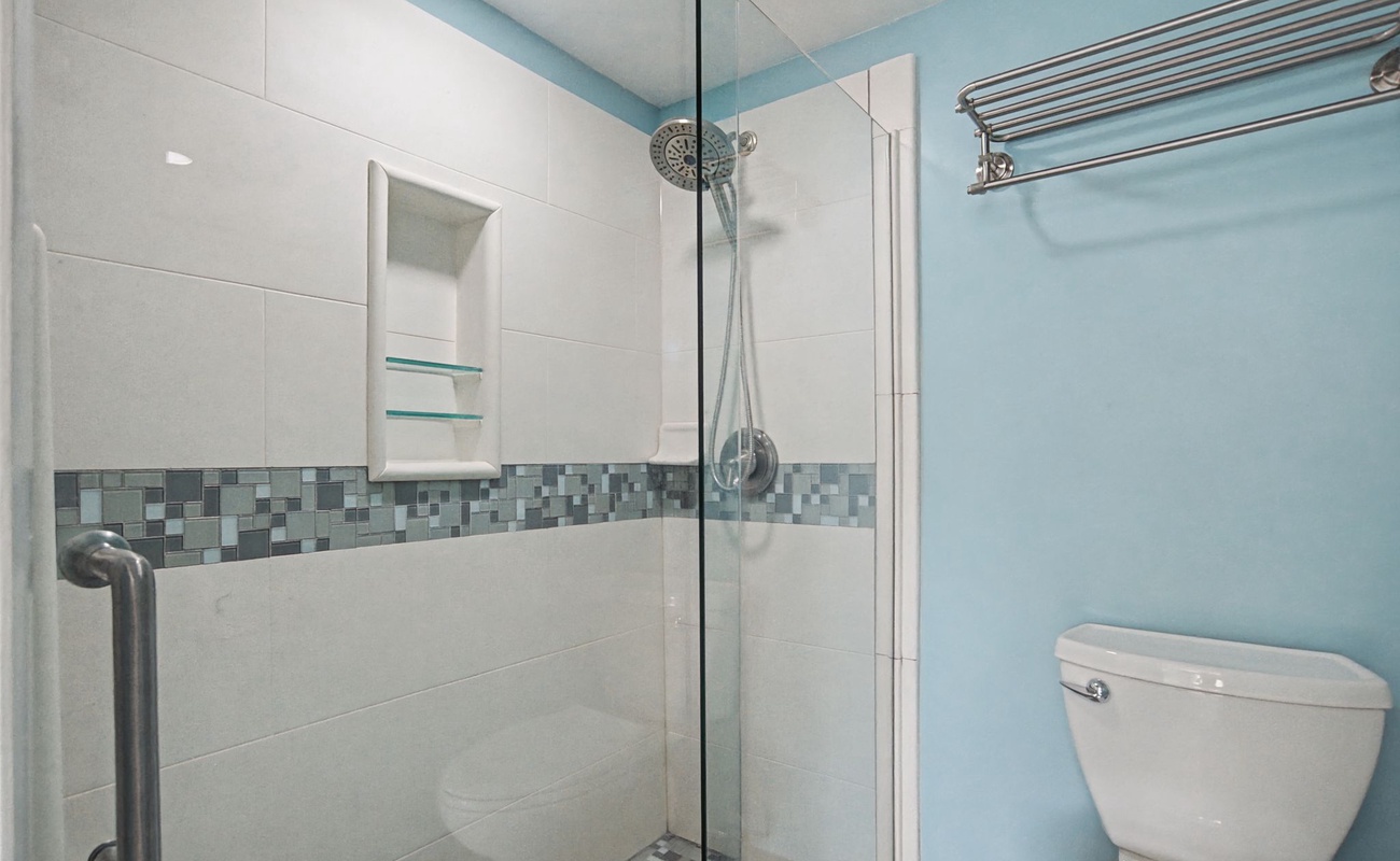 Step into your spotlessly clean private bathroom featuring a spacious walk-in shower with elegant mosaic tile details and fresh fluffy towels.