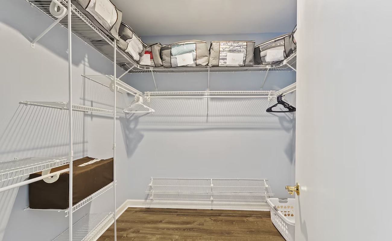 Your private walk-in closet offers generous storage with wire shelving, hanging space, and a convenient laundry basket for effortless organization.