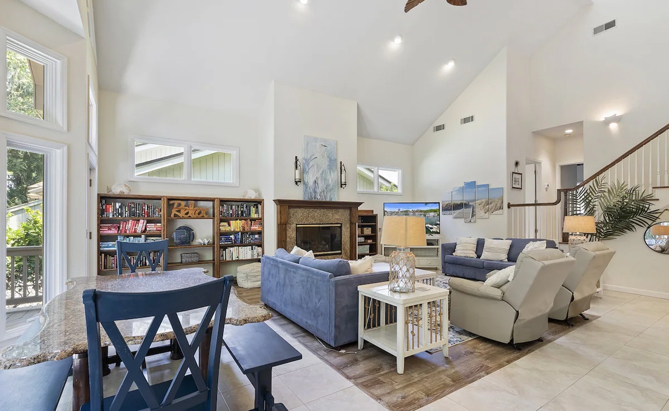 Relax in your spacious living room with soaring ceilings, cozy fireplace, and abundant natural light streaming through large windows.