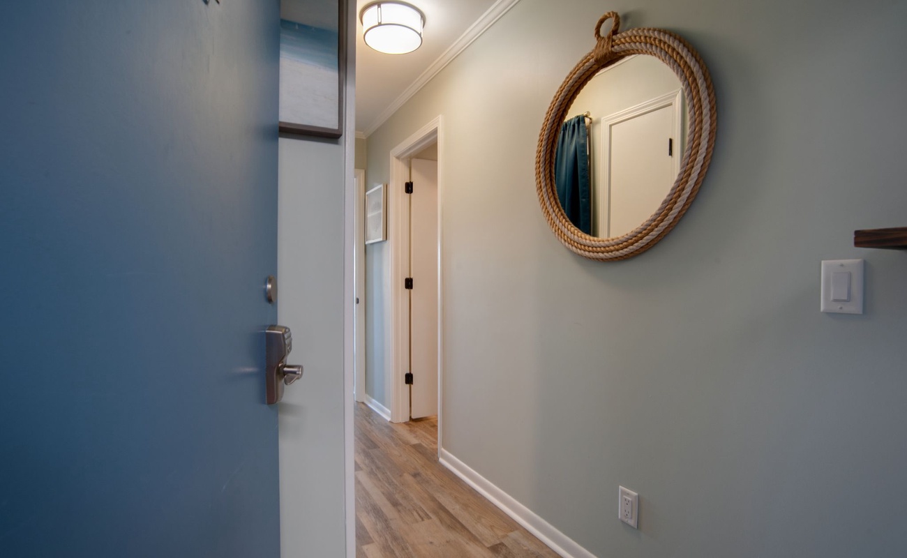 Step into your coastal-inspired entryway, where nautical charm meets modern comfort with rope-wrapped mirrors and soothing blue accents welcoming you home.