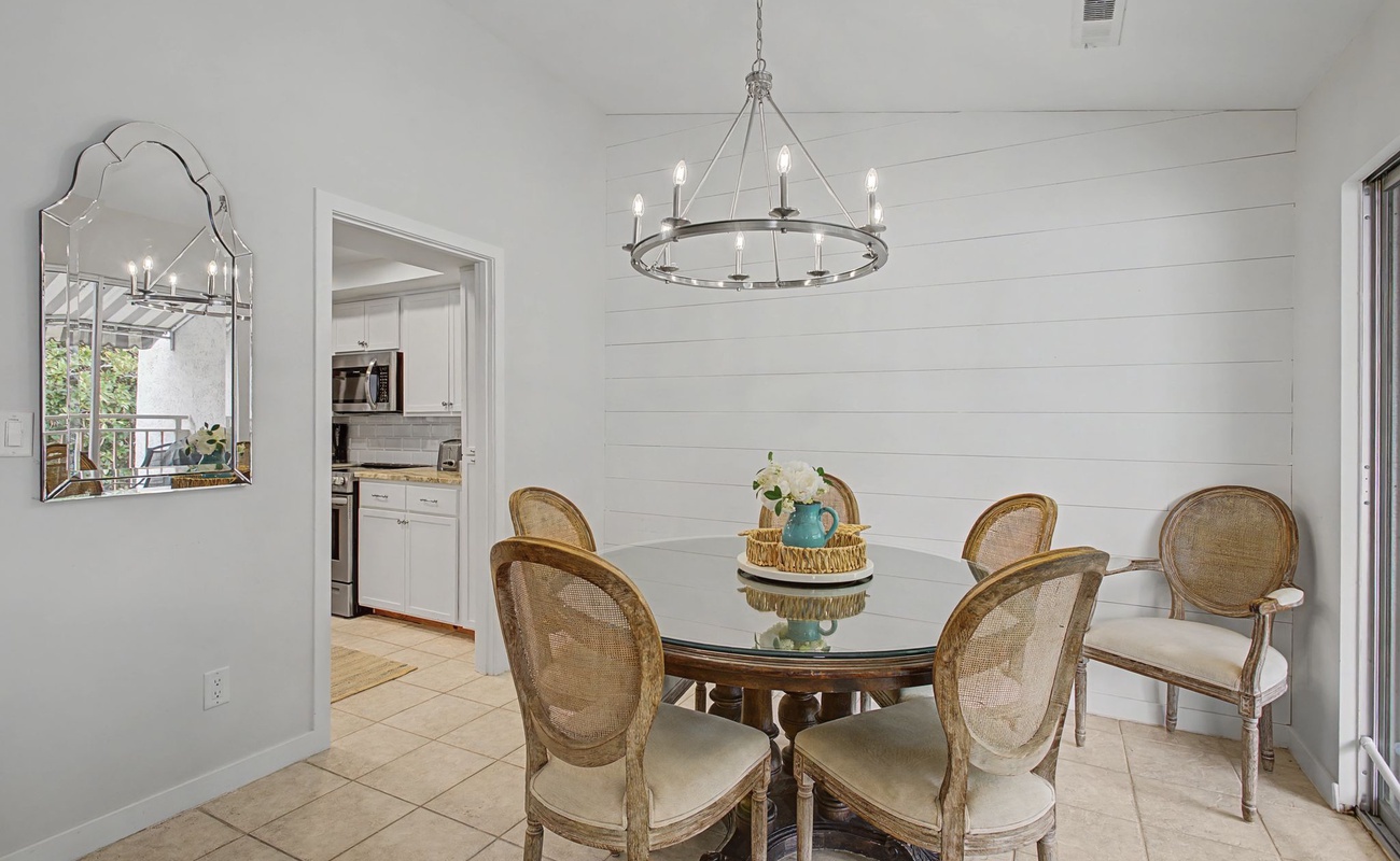 Gather around your elegant glass dining table for memorable meals under the warm glow of a stunning chandelier.