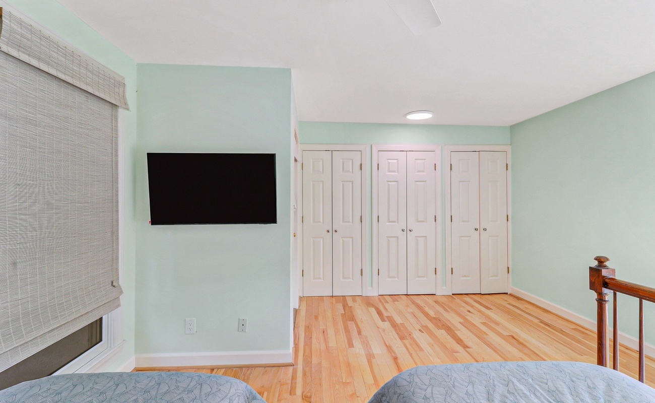 Unwind in your peaceful bedroom with soft mint walls, gleaming hardwood floors, and a mounted TV for your evening entertainment.