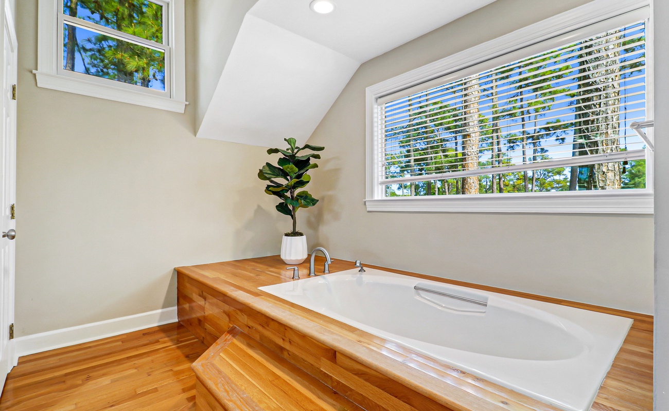 Sink into this luxurious soaking tub surrounded by warm wood accents and natural light streaming through your private windows.