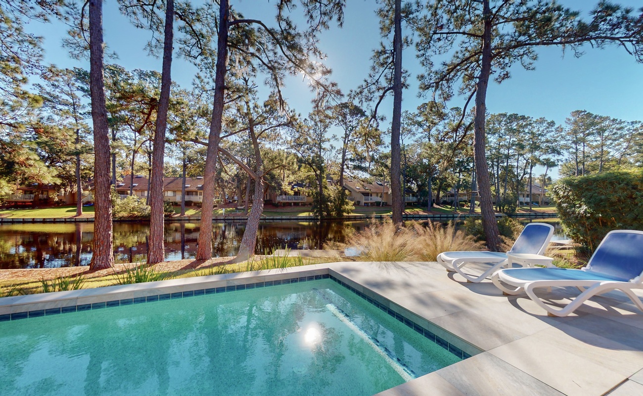 Unwind by your private pool surrounded by towering pines and tranquil water views, where comfortable loungers await your perfect relaxation moment.