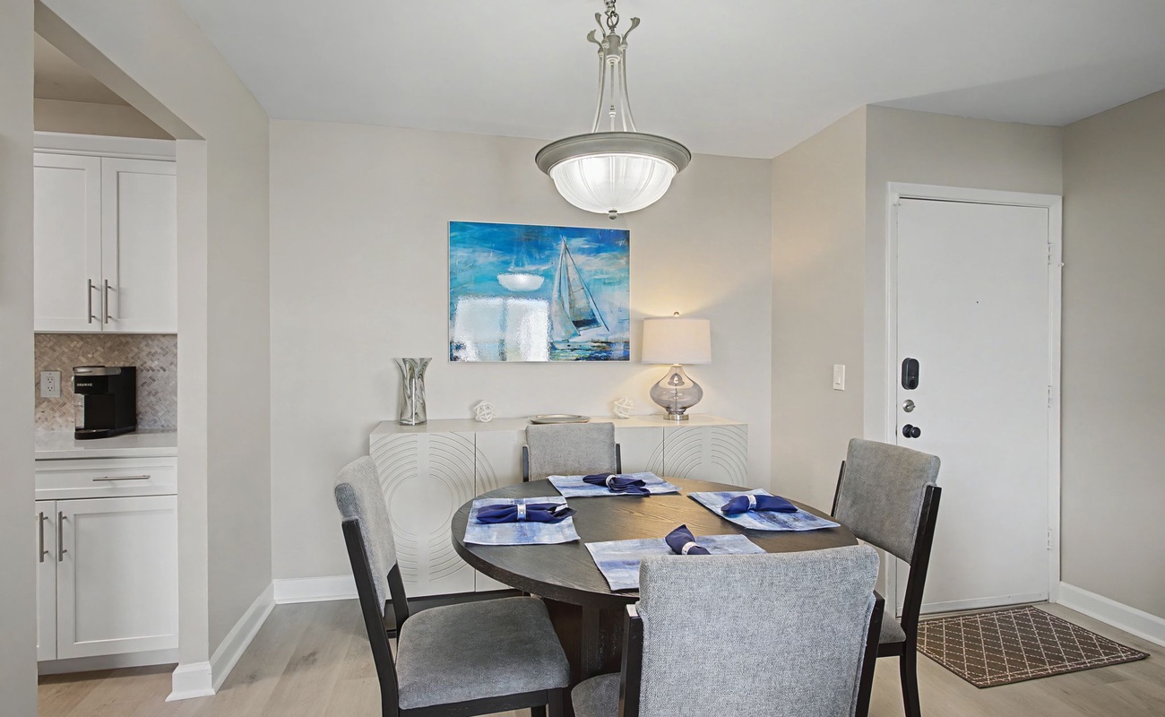 Gather around your elegant dining table for memorable meals beneath coastal artwork and soft pendant lighting.