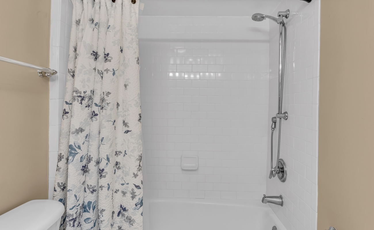 Refresh in your private bathroom featuring a gleaming tub-shower combo with elegant floral curtain and modern fixtures.