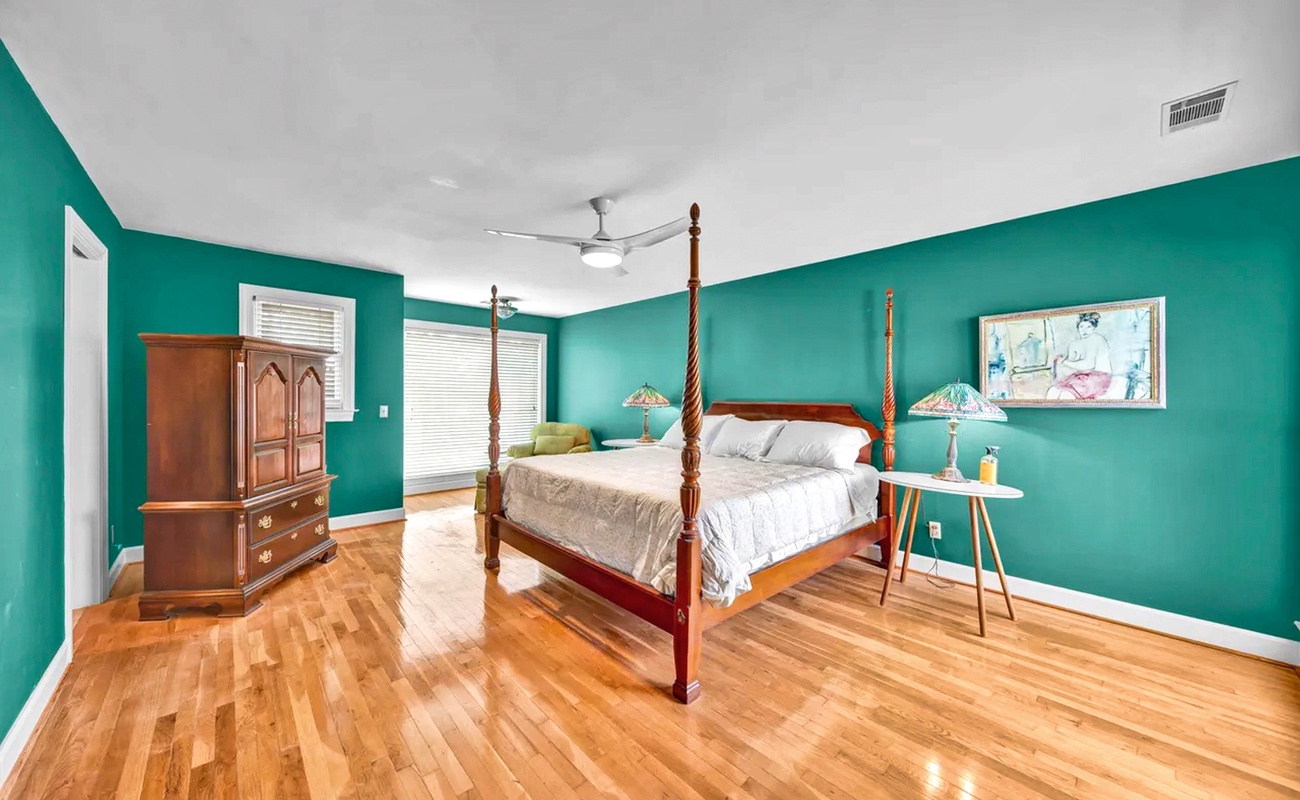 Unwind in your elegant master bedroom with vibrant turquoise walls, gleaming hardwood floors, and a stately four-poster bed.