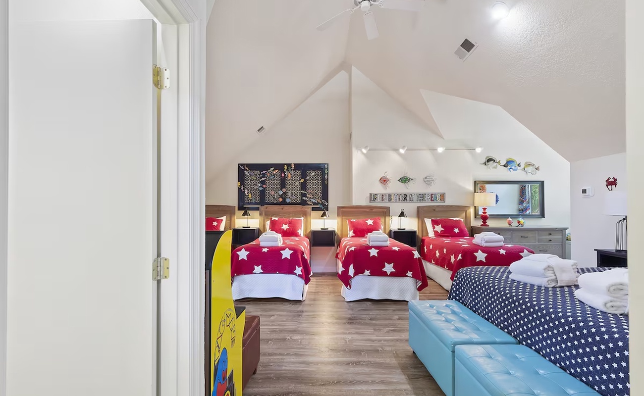 Your family will love this vibrant attic bedroom with star-patterned bedding, custom lighting, and cozy entertainment setup.