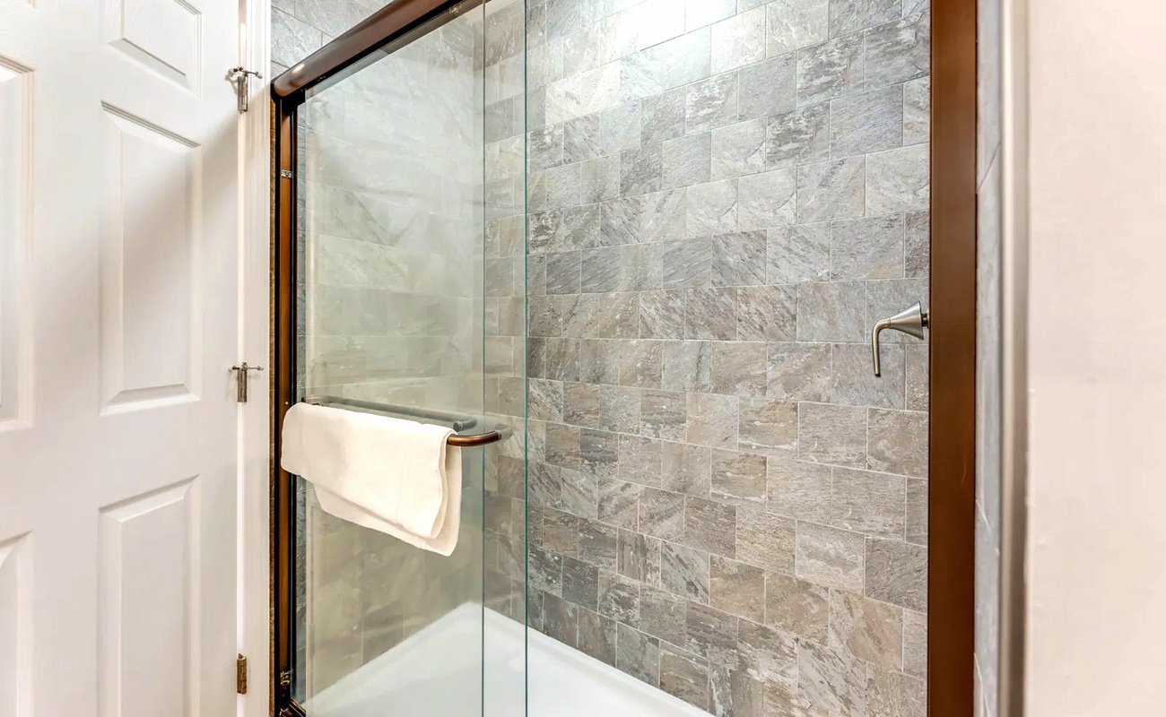 Step into your luxurious glass-enclosed shower featuring elegant natural stone tiles and sleek modern fixtures for a spa-like experience.