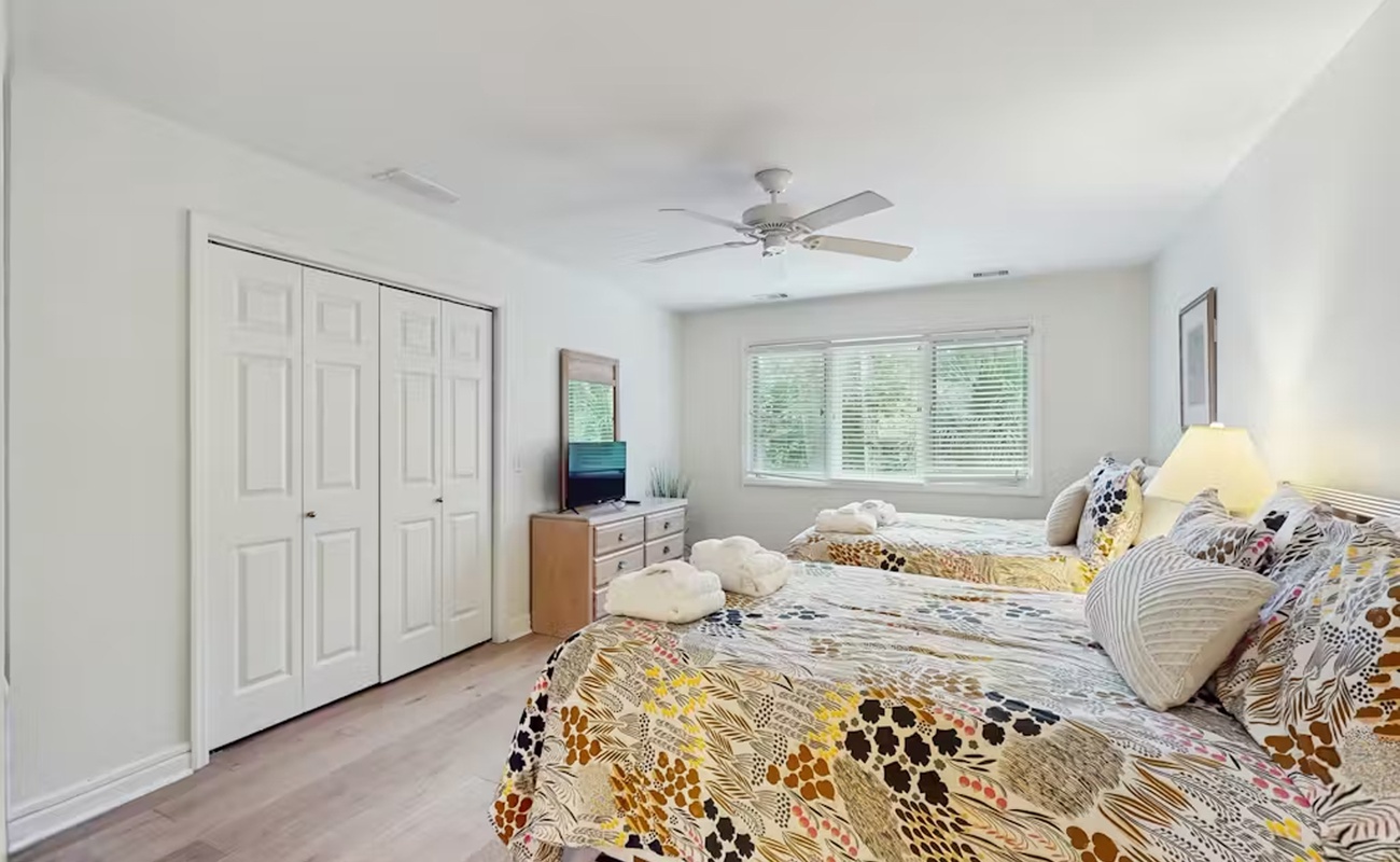 Wake up refreshed in your bright, airy bedroom with twin beds draped in cheerful patterns and gentle natural light.